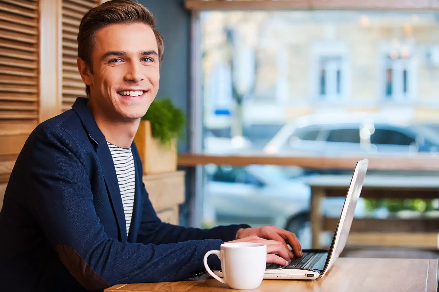 Person sitting at a table with a laptop and a cup of coffee