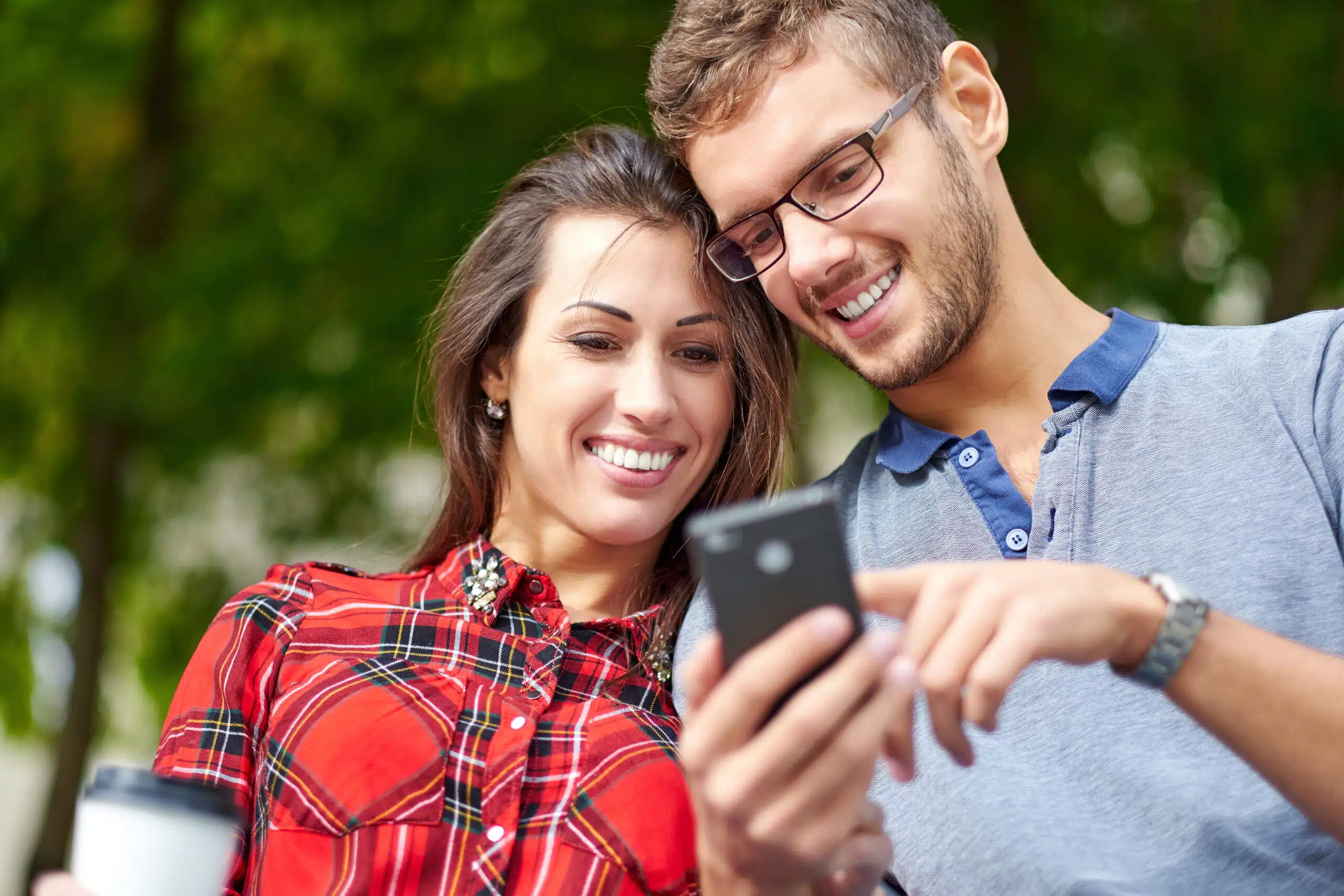 Couple smiling while looking at a smartphone