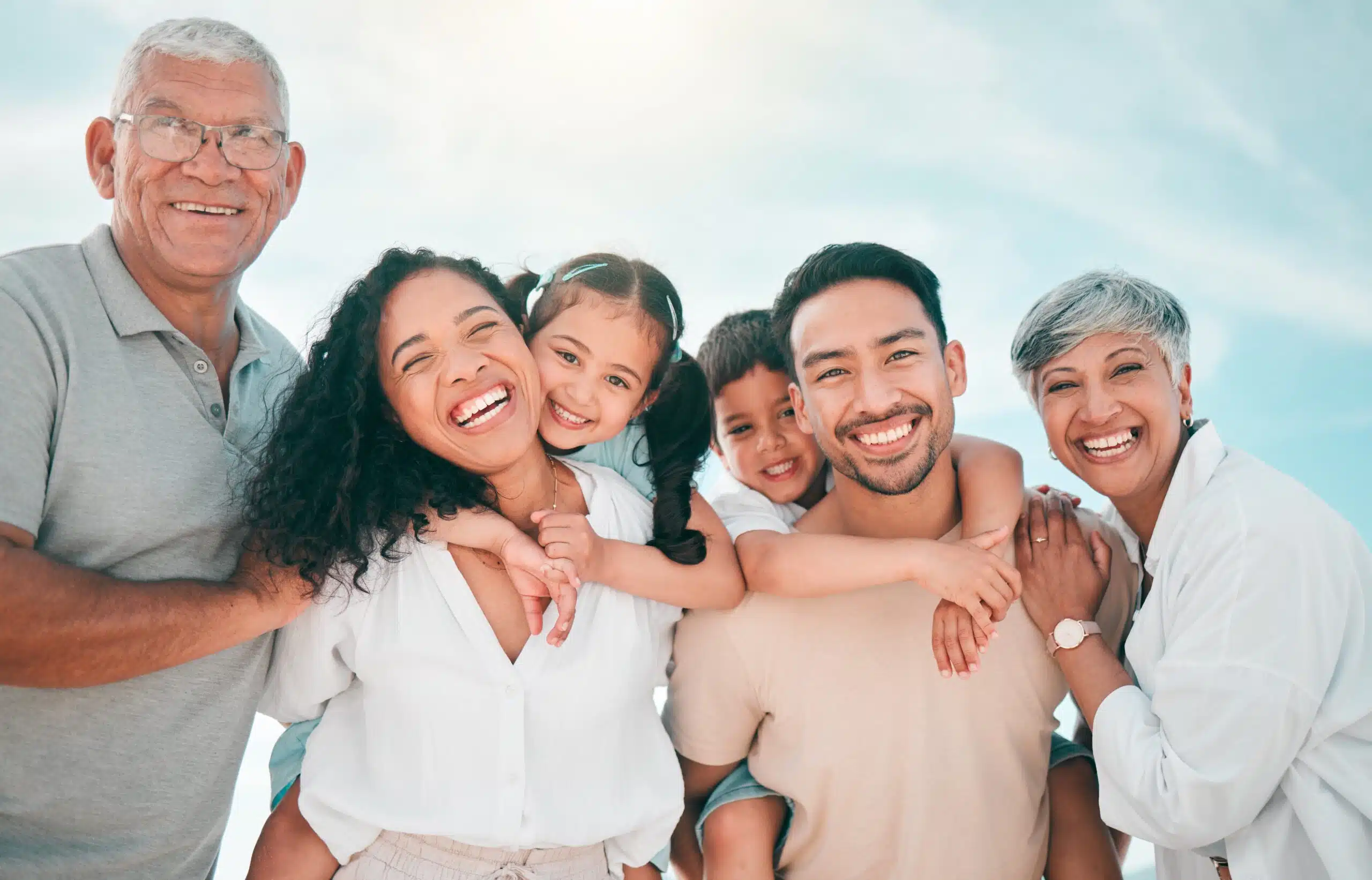 Multigenerational family smiling together outdoors with grandparents, parents, and children