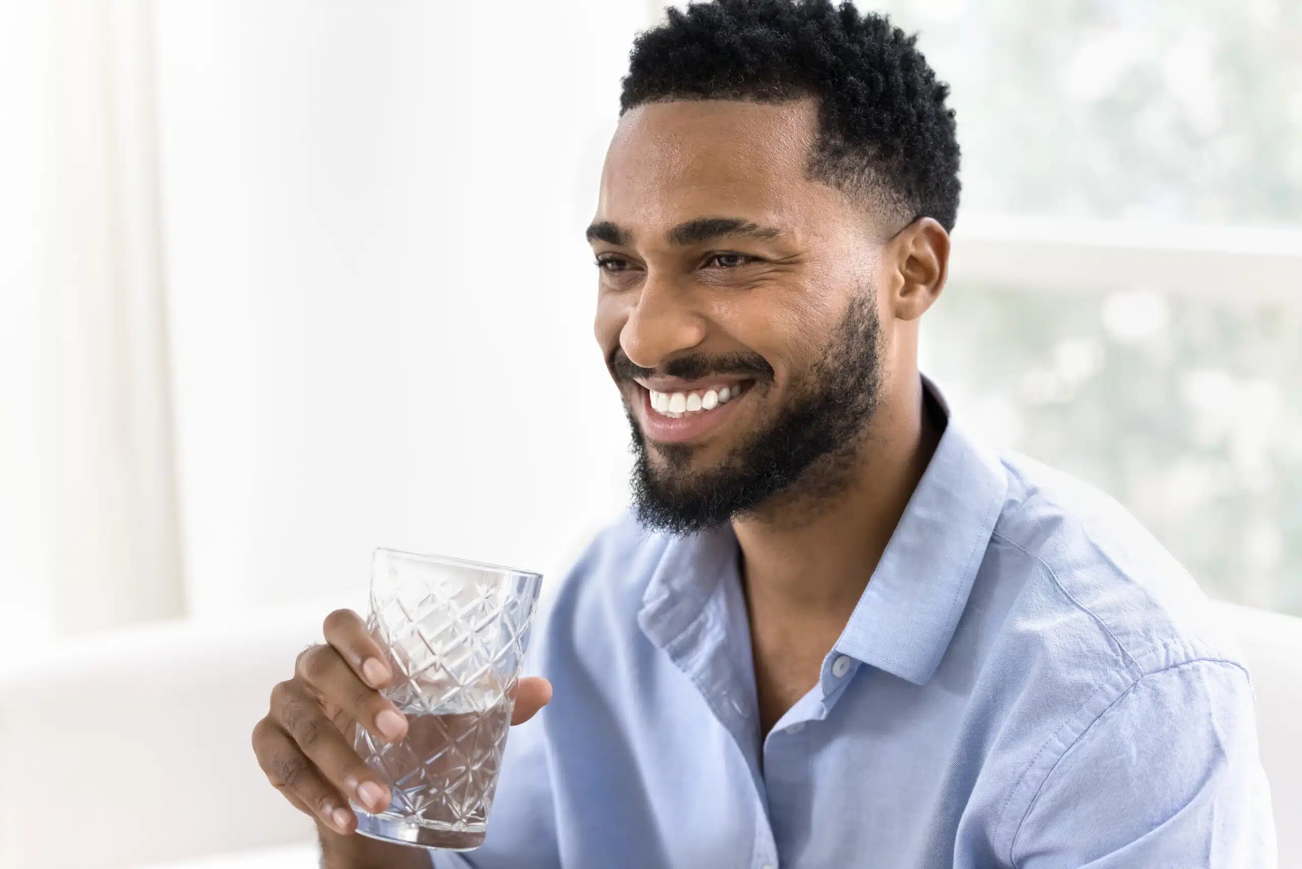 Man smiling while holding a glass of water