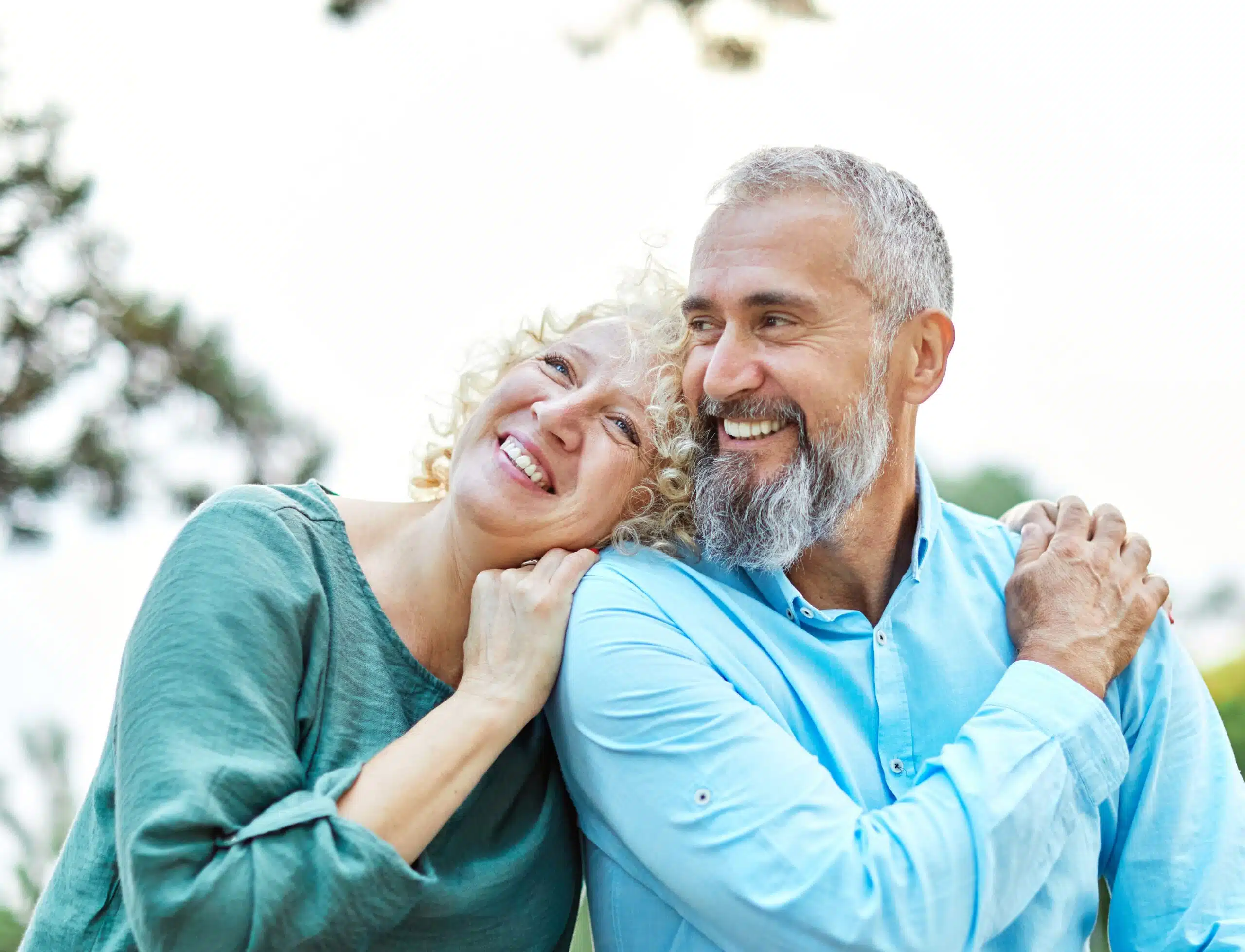 Happy older couple smiling and embracing outdoors, representing a joyful and affectionate relationship