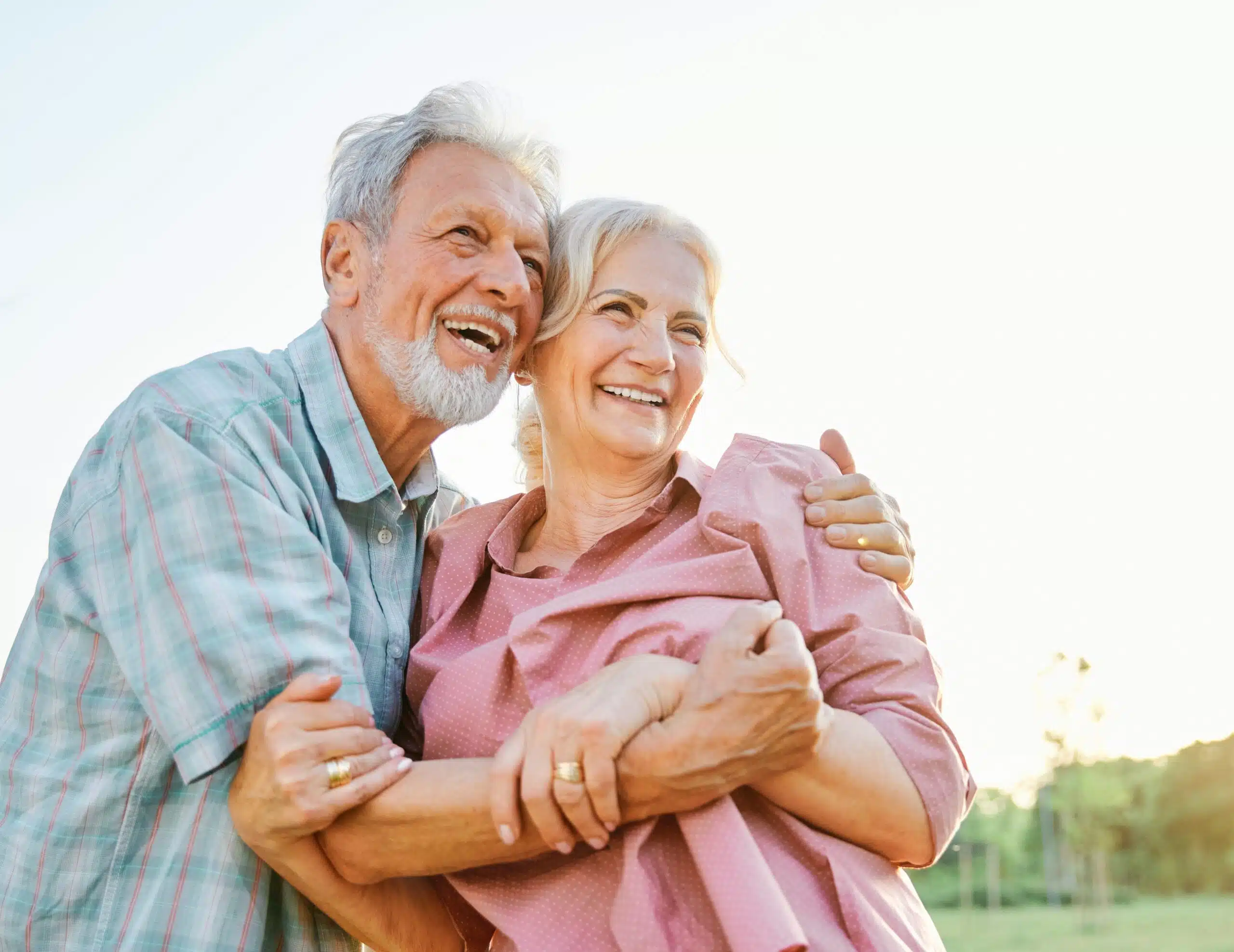 Smiling older couple embracing outdoors, representing confidence and enjoying life together.
