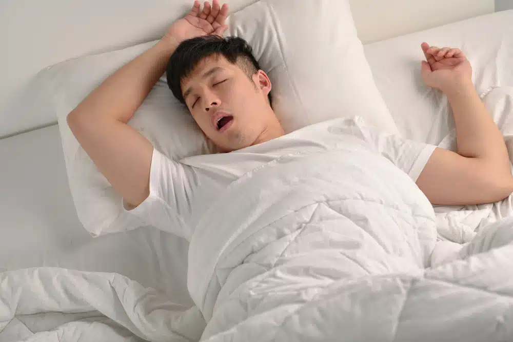 Person sleeping in bed experiencing bruxism and teeth grinding