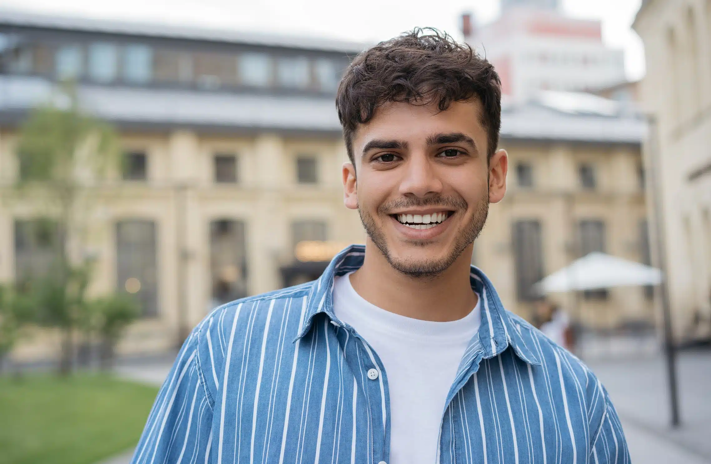 Smiling young man standing outdoors in front of a residential building