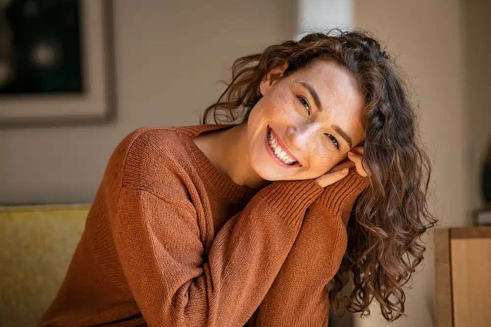 Woman smiling while resting her head on her hand at home