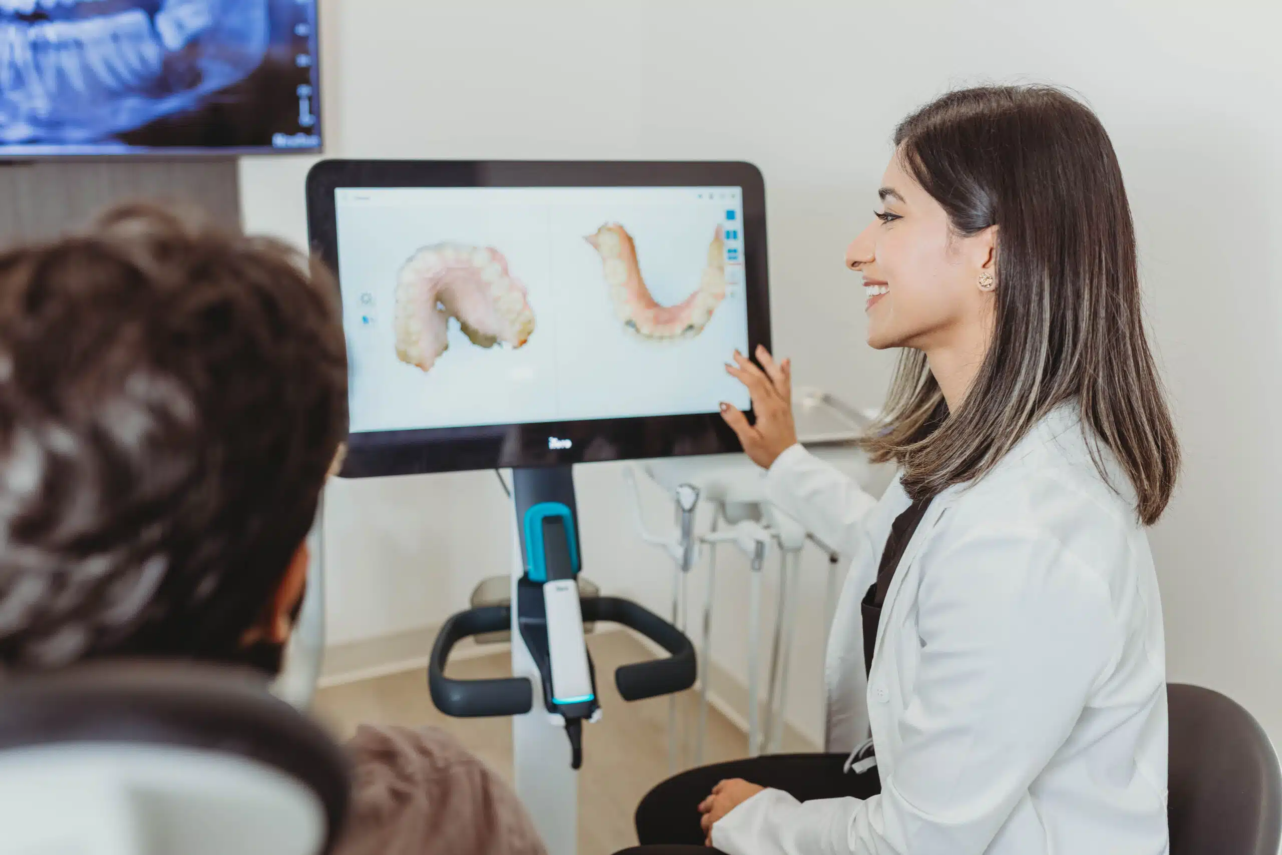 Dentist explaining Invisalign treatment using a digital dental scan to a patient.