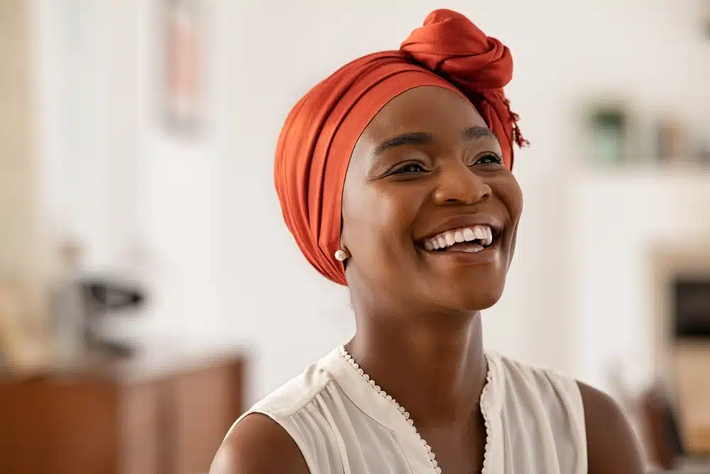 Woman with a bright smile wearing an orange headwrap indoors