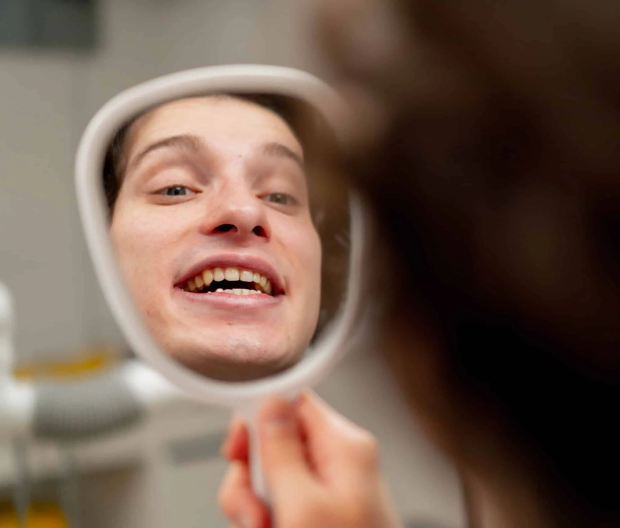 Patient checking tooth discoloration and stains in a mirror