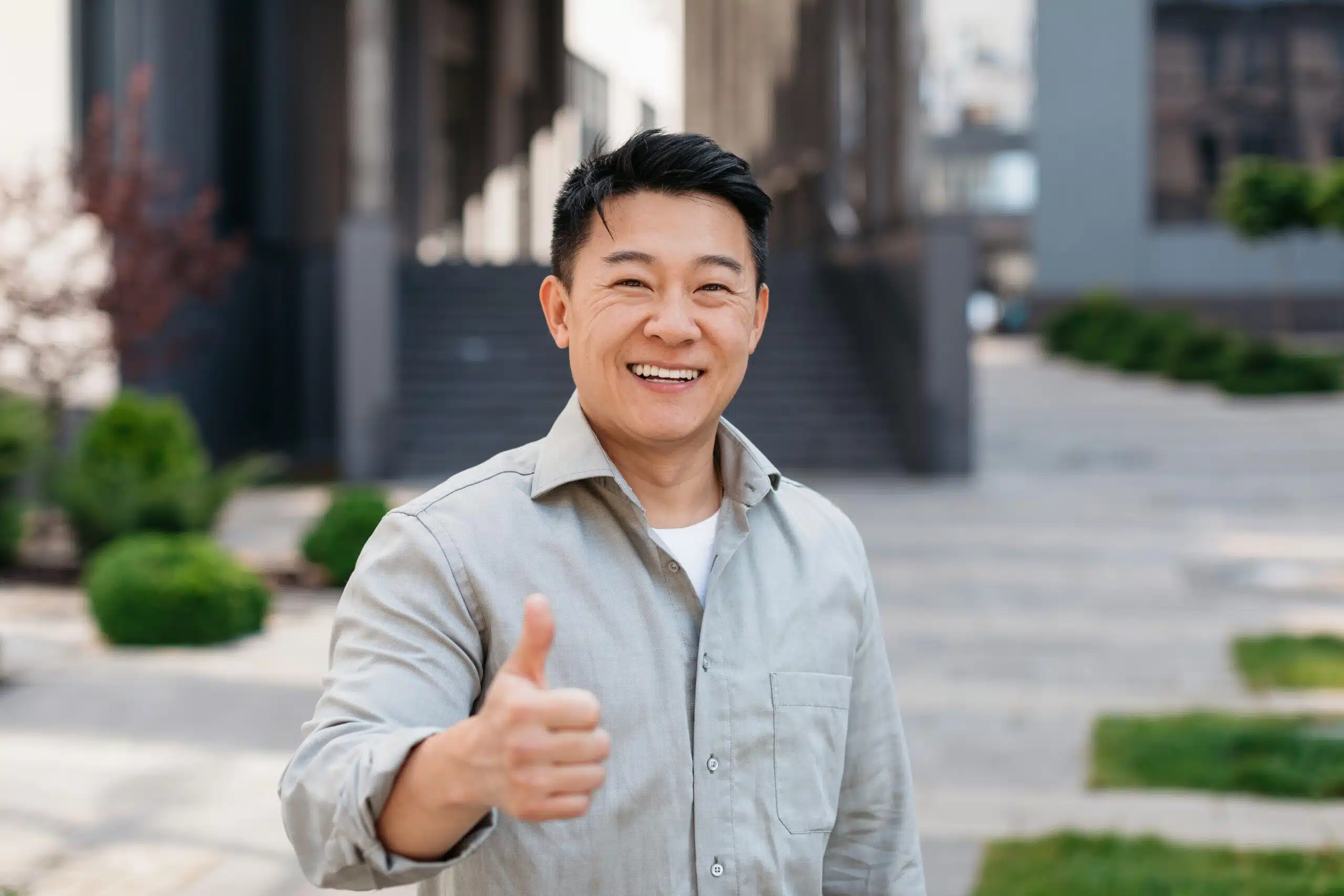 Smiling man giving a thumbs-up outdoors